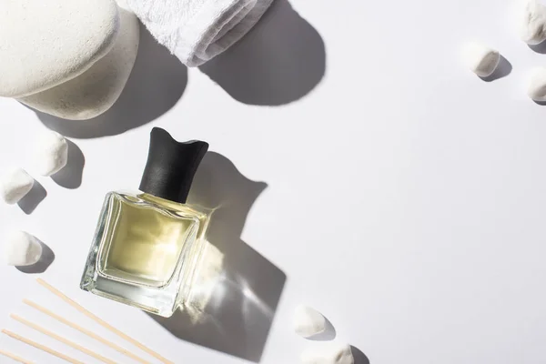 Top view of aroma sticks with perfume in bottle near spa stones and towel on white background — Stock Photo