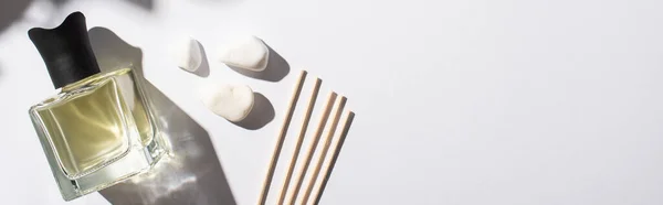 Top view of aroma sticks with perfume in bottle near stones on white background, panoramic shot — Stock Photo