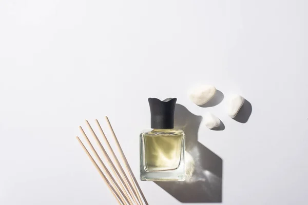 Vue de dessus des bâtons d'arôme avec parfum en bouteille près de pierres sur fond blanc — Photo de stock