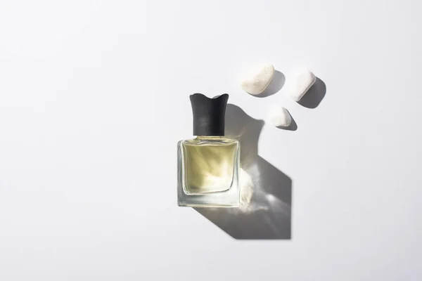 Top view of home perfume in bottle near stones on white background — Stock Photo