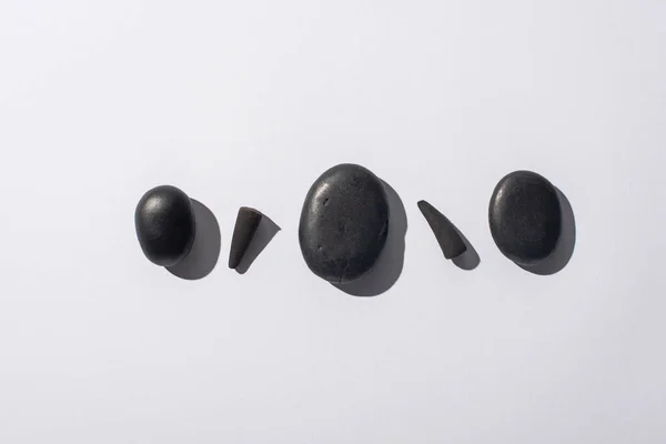 Vista superior de cones de incenso preto e pedras de spa no fundo branco — Fotografia de Stock