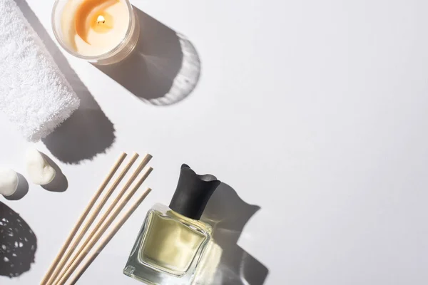 Top view of aroma sticks with perfume in bottle near cotton towel, stones and candle on white background — Stock Photo