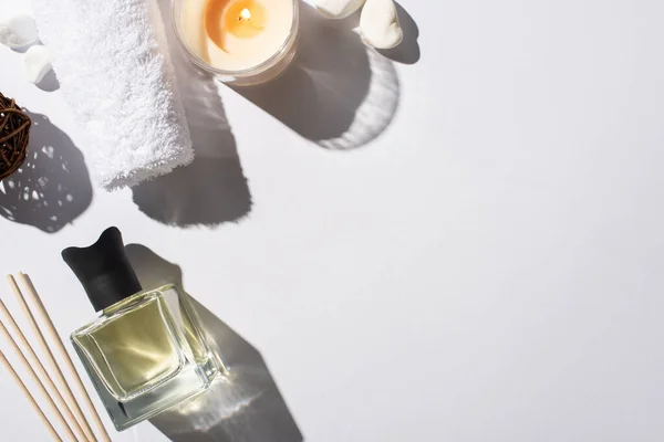 Top view of aroma sticks with perfume in bottle near cotton towel, stones and candle on white background — Stock Photo