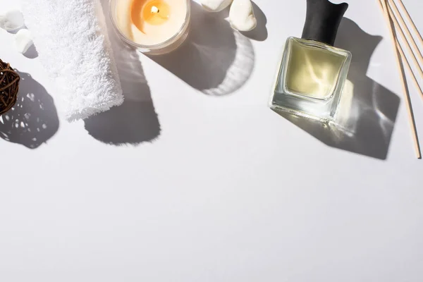 Top view of aroma sticks with perfume in bottle near cotton towel, stones and candle on white background — Stock Photo