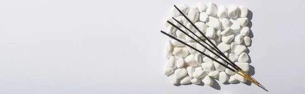 Top view of aroma sticks on square made of stones on white background, panoramic shot — Stock Photo