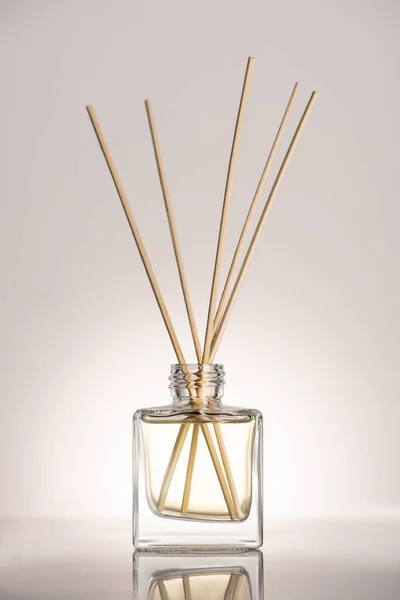 Дерев'яні палички в парфумах у пляшці на бежевому фоні — стокове фото