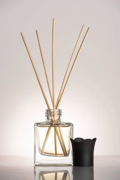 Wooden sticks in perfume in bottle on beige background — Stock Photo