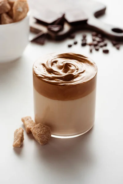 Foyer sélectif de délicieux café Dalgona en verre près de la cassonade sur fond blanc — Photo de stock