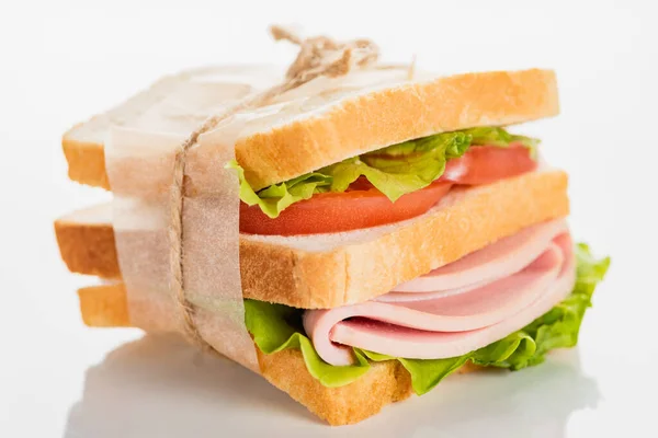 Delicioso sándwich fresco con salchicha en rodajas y lechuga en la superficie blanca - foto de stock