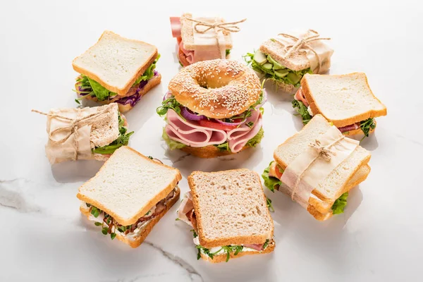 Свежие бутерброды вокруг бублика на мраморной белой поверхности — Stock Photo