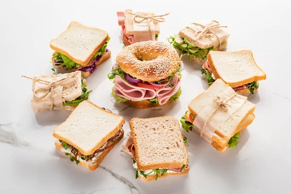 Sanduíches frescos em torno de bagel na superfície branca de mármore — Fotografia de Stock