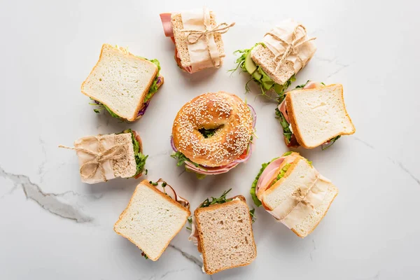 Draufsicht auf frische Sandwiches rund um Bagel auf marmorweißer Oberfläche — Stockfoto