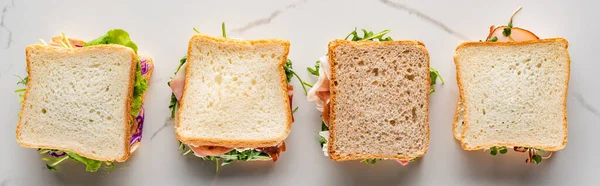 Top view of fresh sandwiches on marble white surface, panoramic shot — Stock Photo