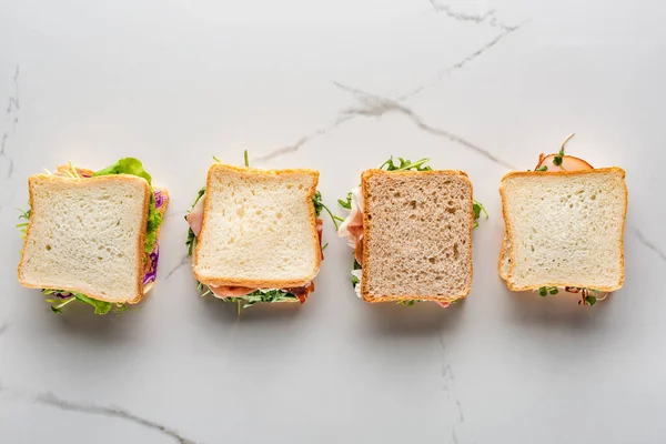 Vue de dessus des sandwichs frais sur la surface en marbre blanc — Photo de stock