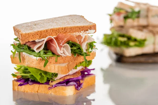Foco seletivo de sanduíches frescos com arugula e carne na superfície branca — Fotografia de Stock