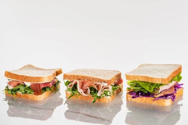 Sandwichs verts frais avec avocat et jamon sur une surface en marbre blanc — Photo de stock