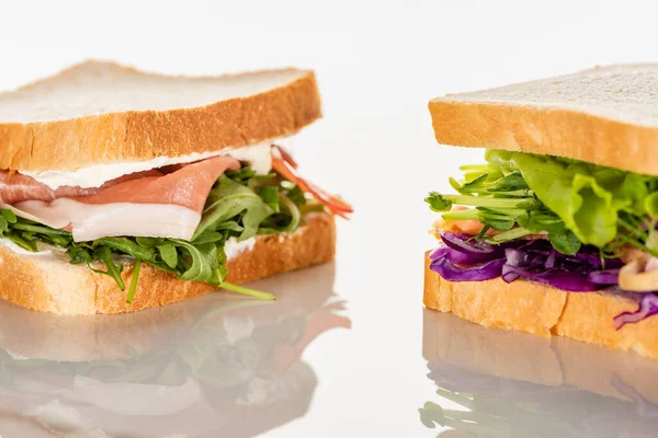 Fresh green sandwiches with prosciutto on white surface — Stock Photo