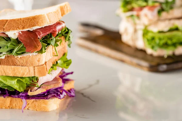 Selective focus of fresh sandwiches with meat on marble white surface — Stock Photo