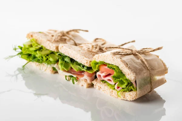 Selektiver Schwerpunkt frischer grüner Sandwiches mit Avocado und Fleisch auf weißer Oberfläche — Stockfoto