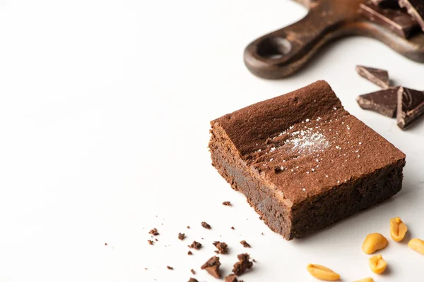 Delicious brownie piece near nuts and chocolate on white background — Stock Photo