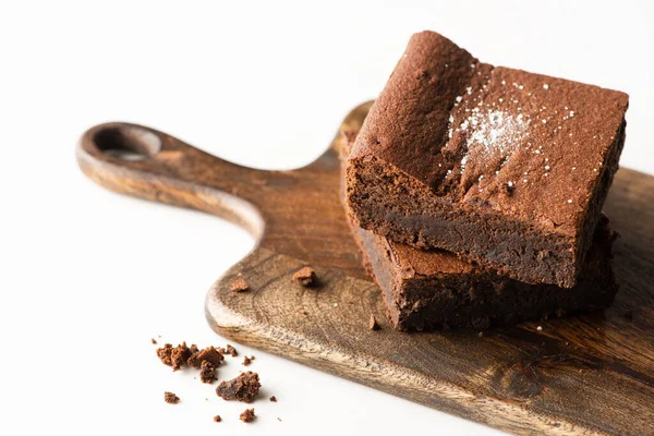 Deliciosos pedaços de brownie na placa de corte de madeira no fundo branco — Fotografia de Stock
