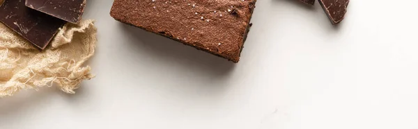 Draufsicht auf köstliches Brownie-Stück mit Schokolade auf weißem Hintergrund, Panoramaaufnahme — Stockfoto