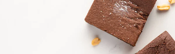 Top view of delicious brownie pieces with nuts on white background, panoramic shot — Stock Photo