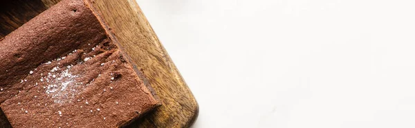 Draufsicht auf köstliches Brownie-Stück auf Holzschneidebrett auf weißem Hintergrund, Panoramaaufnahme — Stockfoto