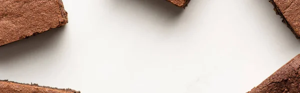 Top view of delicious brownie pieces on white background, panoramic shot — Stock Photo