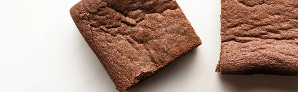 Vista superior de deliciosas piezas de brownie sobre fondo blanco, plano panorámico — Stock Photo