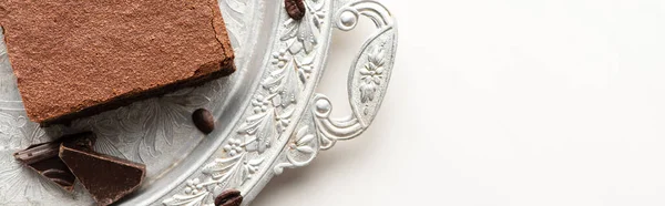 Vista superior de deliciosa peça brownie com grãos de café e chocolate na bandeja de prata no fundo branco, tiro panorâmico — Fotografia de Stock