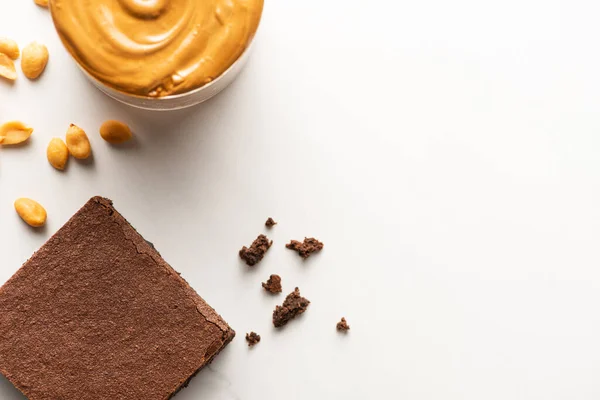 Vue du dessus de délicieux morceau de brownie avec beurre d'arachide et noix sur fond blanc — Photo de stock