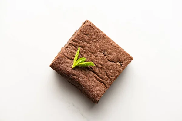 Draufsicht auf köstliches Brownie-Stück mit Minze auf weißem Hintergrund — Stockfoto