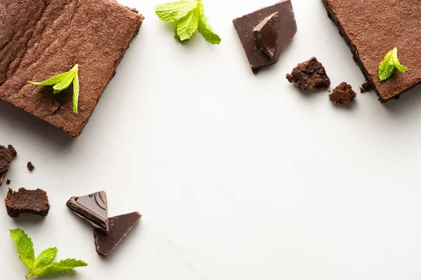 Draufsicht auf köstliche Brownie-Stücke mit Minze und Schokolade auf weißem Hintergrund — Stockfoto