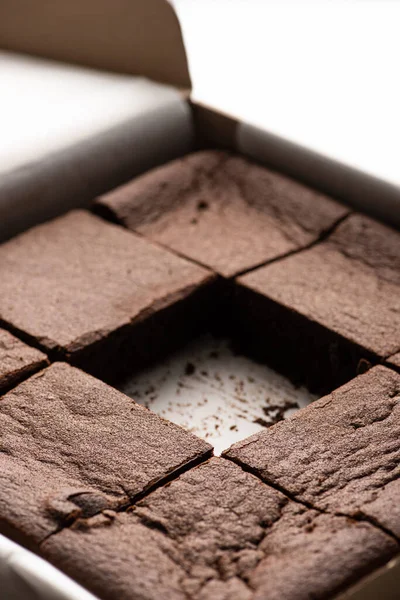 Close up view of delicious brownie pieces in cardboard box on white background — Stock Photo