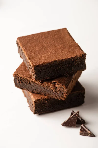 Deliziosi pezzi di brownie con cioccolato fondente su sfondo bianco — Foto stock