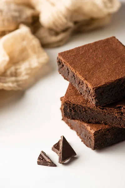 Foco seletivo de deliciosas peças de brownie com chocolate escuro no fundo branco — Fotografia de Stock
