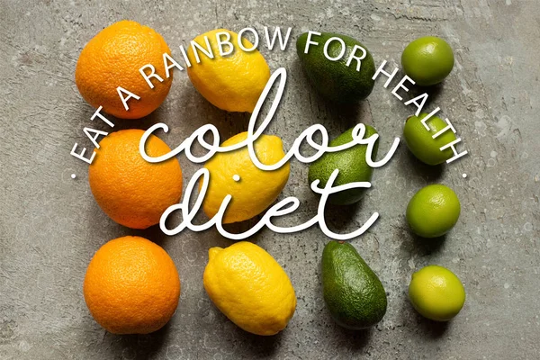 Flat lay with colorful oranges, avocado, limes and lemons on grey concrete surface, color diet illustration — Stock Photo