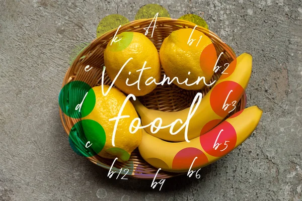 Vista superior de plátanos coloridos y limones en canasta de mimbre sobre superficie de hormigón gris, ilustración de alimentos vitamínicos - foto de stock