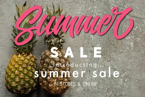 Top view of ripe pineapples on grey concrete surface with summer sale illustration — Stock Photo