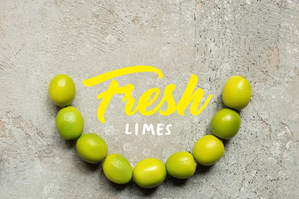 Vista superior de limas verdes sobre superficie de hormigón gris con ilustración de limas frescas — Stock Photo