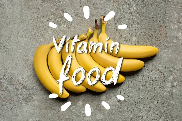 Вид зверху барвистих смачних бананів на сірій бетонній поверхні з ілюстрацією вітамінної їжі — стокове фото
