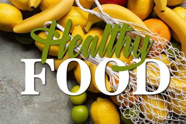 Vista superior de frutas coloridas y bolsa de cuerda en la superficie de hormigón gris, ilustración de alimentos saludables - foto de stock