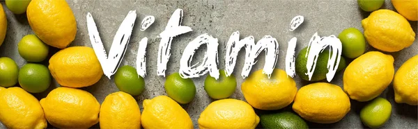 Top view of colorful limes, avocado and lemons on grey concrete surface with vitamin illustration, panoramic shot — Stock Photo