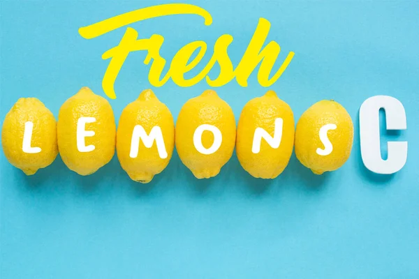 Vista superior de limones amarillos maduros y letra C sobre fondo azul, ilustración de limones frescos - foto de stock