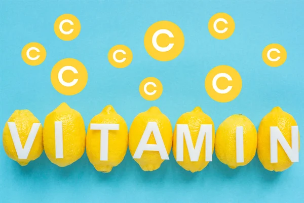 Vista superior de limões amarelos maduros e ilustração de vitamina C no fundo azul — Fotografia de Stock