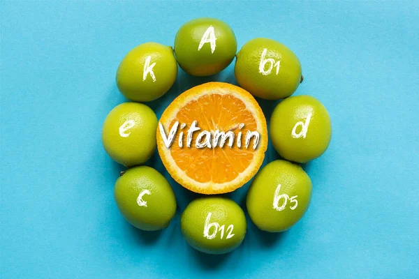 Vista superior de naranja madura y limas dispuestas en círculo sobre fondo azul, ilustración de vitaminas - foto de stock