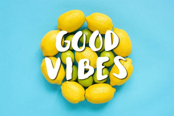 Top view of ripe yellow lemons and limes arranged in circles on blue background, good vibes illustration — Stock Photo