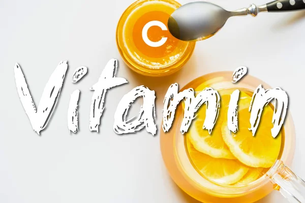 Draufsicht auf heißen Tee mit Zitrone in der Nähe von Honig mit Löffel auf weißem Hintergrund, Vitamin C Illustration — Stockfoto