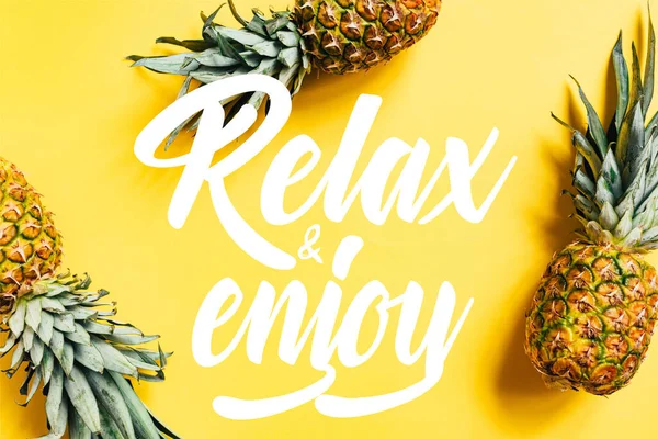 Top view of fresh tasty pineapples on yellow background with relax and enjoy illustration — Stock Photo